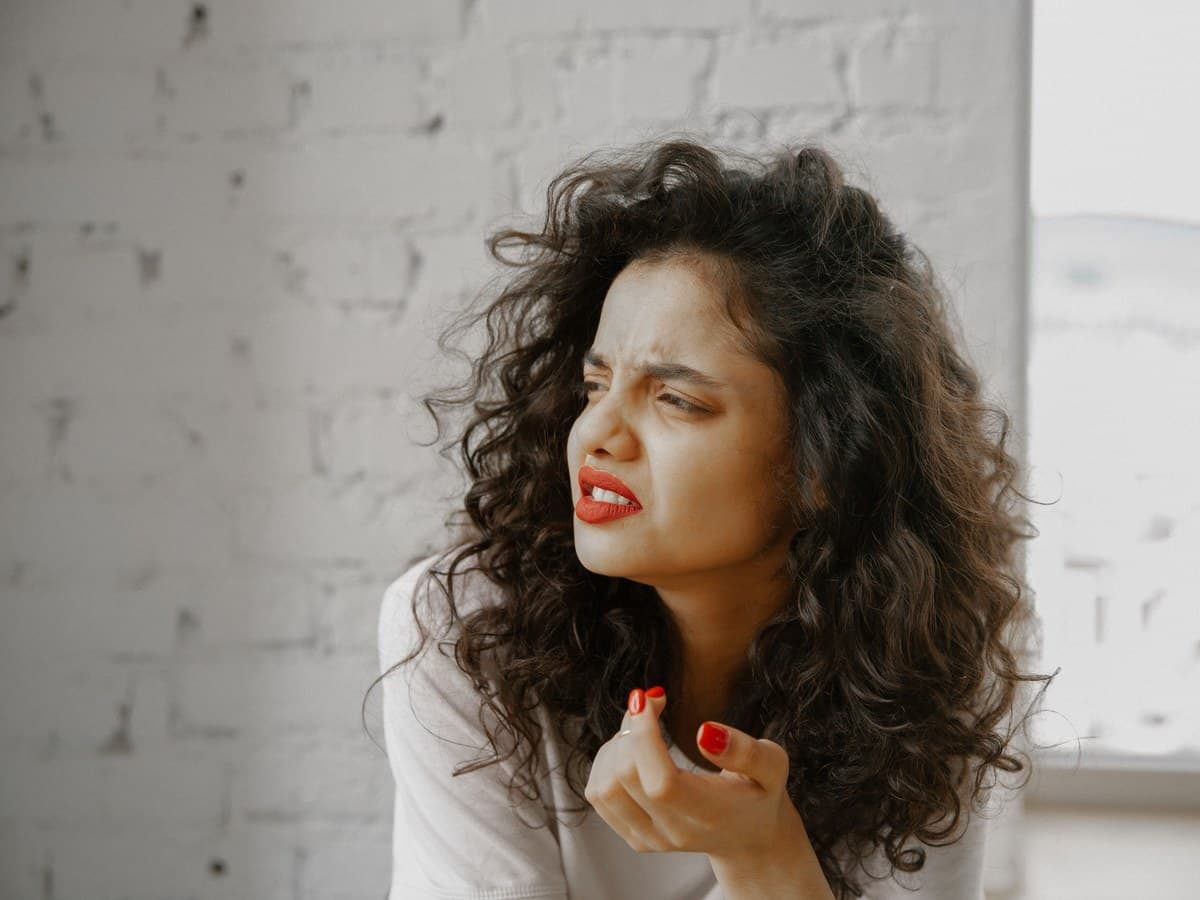 A woman indoors with her brow drawn, mid expression