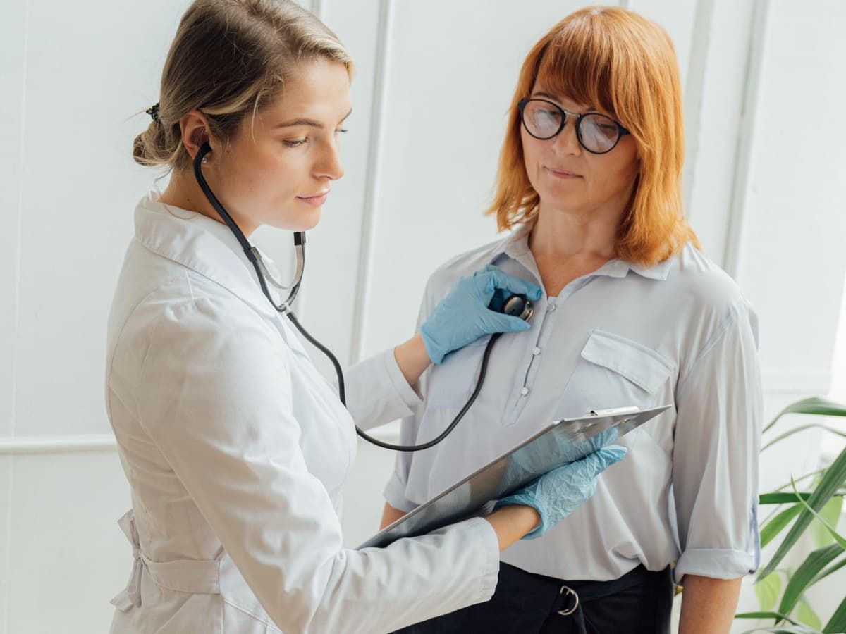 A doctor listening to a patient with a stethoscope during an appointment